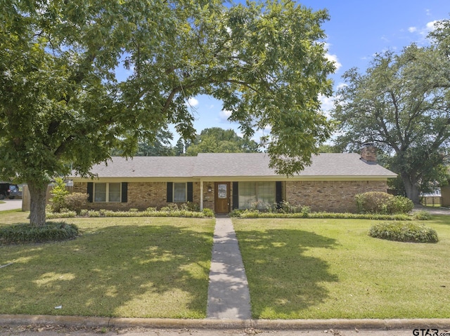 909 Elizabeth St, Gilmer, TX 75644 - view of front of house featuring a chimney, a front lawn, and brick siding