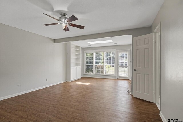 909 Elizabeth St, Gilmer, TX 75644 - empty room with wood finished floors, a skylight, baseboards, and ceiling fan
