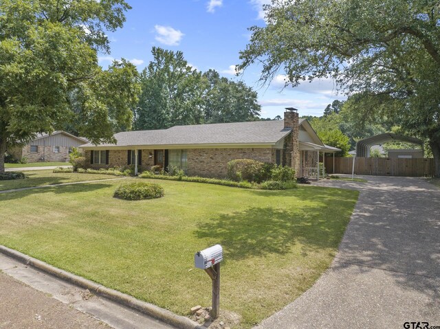 909 Elizabeth St, Gilmer, TX 75644 - view of front of home with a detached carport, a chimney, driveway, and brick siding