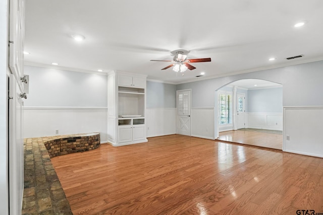 unfurnished living room with light hardwood / wood-style floors, ceiling fan, and crown molding