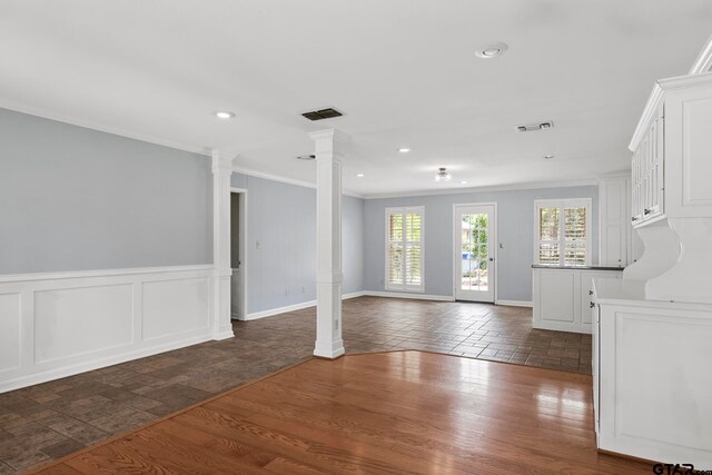 spare room with dark wood-type flooring, crown molding, and decorative columns