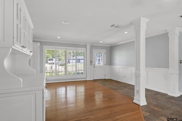 909 Elizabeth St, Gilmer, TX 75644 - foyer entrance featuring ornamental molding, decorative columns, stone tile flooring, wainscoting, and recessed lighting