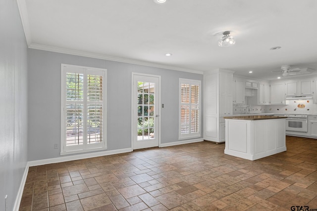 kitchen featuring sink, tasteful backsplash, white appliances, crown molding, and white cabinets