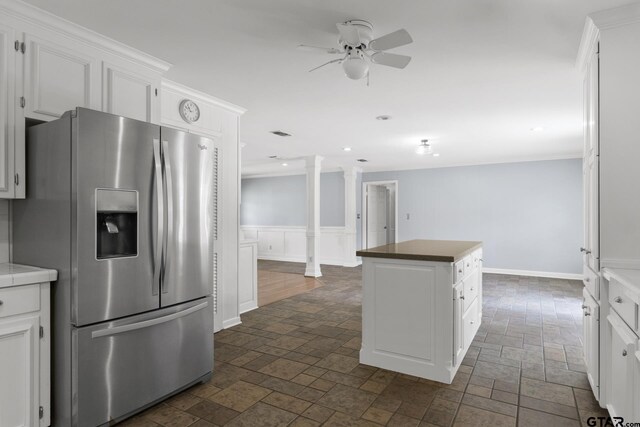 909 Elizabeth St, Gilmer, TX 75644 - kitchen featuring stainless steel fridge, a kitchen island, a ceiling fan, stone tile flooring, and a wainscoted wall