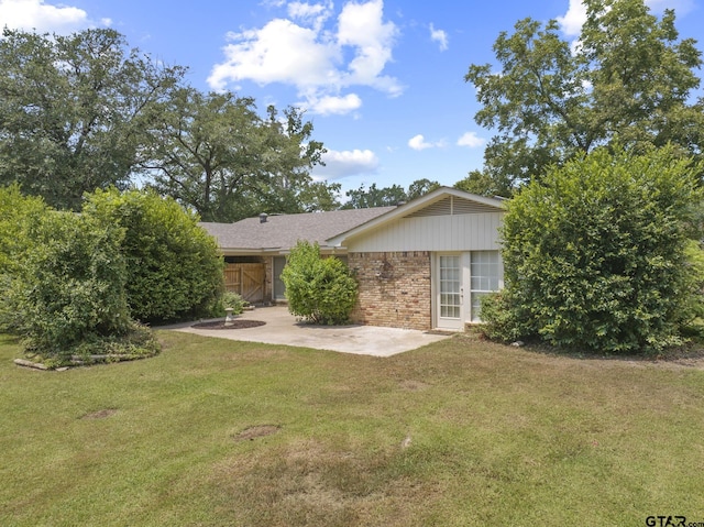909 Elizabeth St, Gilmer, TX 75644 - back of property with brick siding, a patio area, and a yard