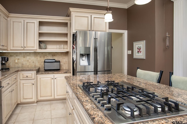 kitchen featuring appliances with stainless steel finishes, cream cabinets, decorative light fixtures, and crown molding