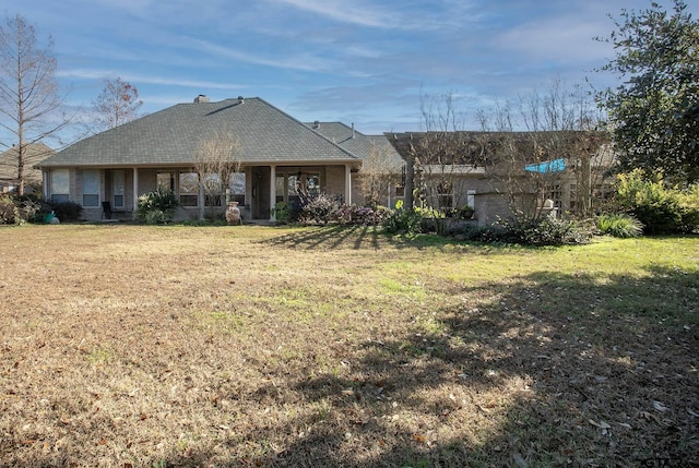 view of front of property with brick siding, a chimney, and a front yard