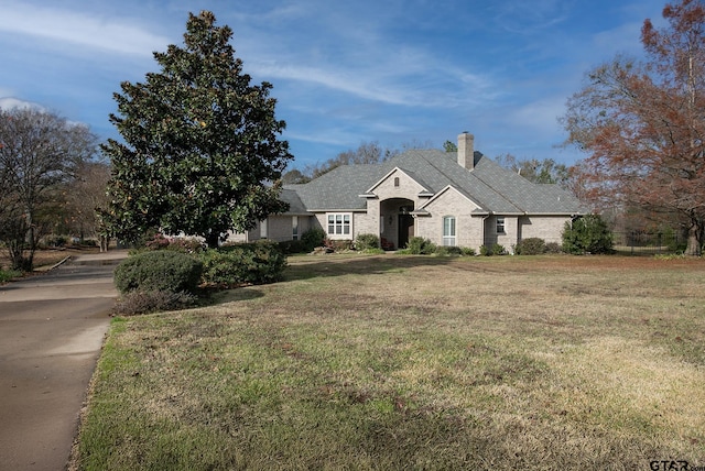 french country inspired facade with a front lawn and a chimney