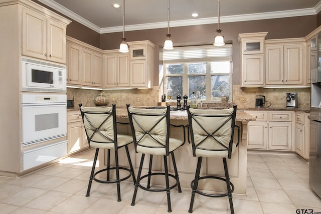 kitchen with decorative light fixtures, a center island with sink, cream cabinets, glass insert cabinets, and white appliances