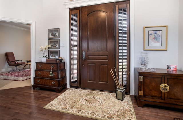 foyer entrance with crown molding and dark wood-style flooring