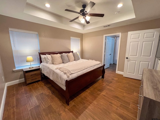 bedroom featuring dark hardwood / wood-style floors, ceiling fan, and a raised ceiling