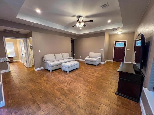 living room featuring ceiling fan, a tray ceiling, and hardwood / wood-style flooring