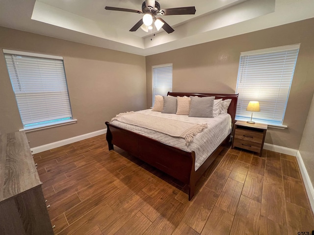 bedroom with ceiling fan and a tray ceiling