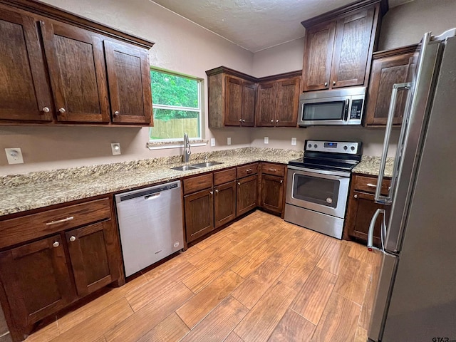 kitchen with light stone countertops, sink, dark brown cabinetry, and stainless steel appliances