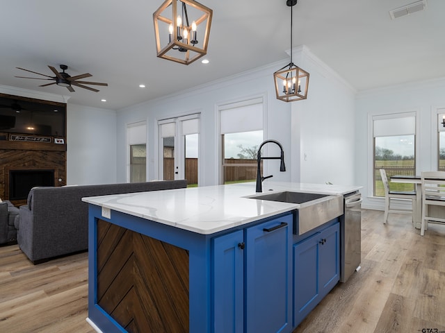 kitchen with visible vents, blue cabinets, open floor plan, and a sink