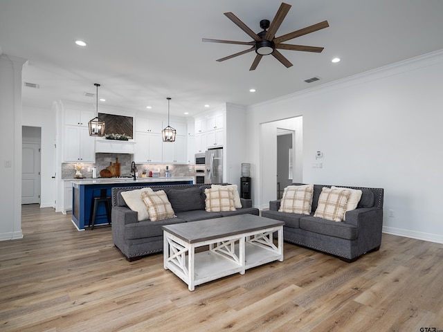 living area with visible vents, light wood-style floors, and a ceiling fan