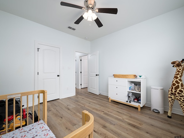 bedroom featuring light wood finished floors, visible vents, ceiling fan, and baseboards