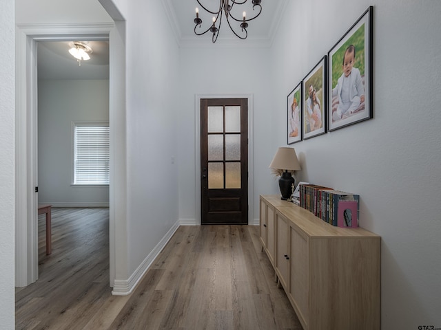 entryway with a chandelier, light wood-style flooring, baseboards, and ornamental molding