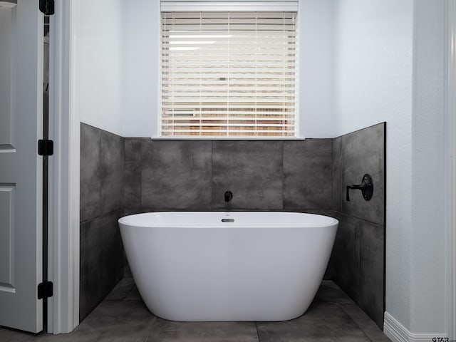 full bathroom with tile patterned flooring, tile walls, and a freestanding tub