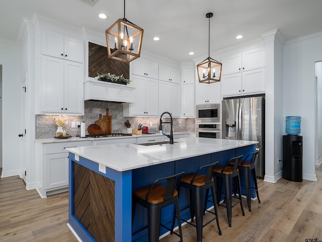 kitchen with an inviting chandelier, light wood-style flooring, appliances with stainless steel finishes, and a sink