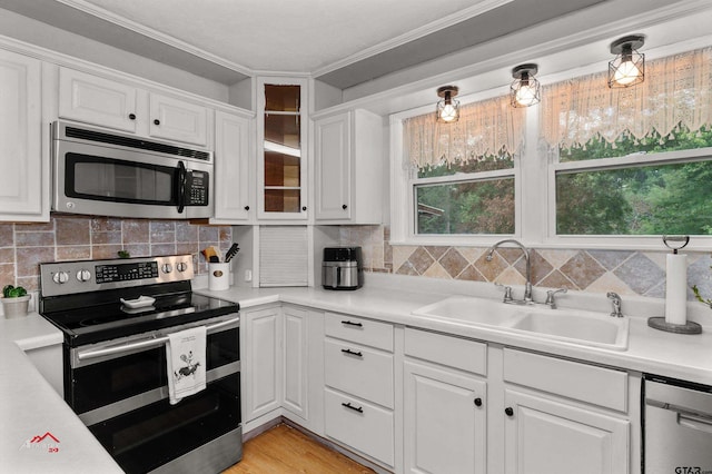 kitchen featuring sink, white cabinets, stainless steel appliances, crown molding, and light wood-type flooring