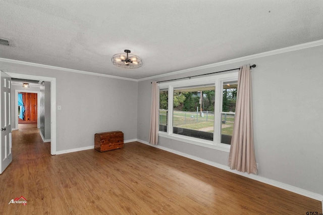 empty room with ornamental molding, hardwood / wood-style floors, a textured ceiling, and a notable chandelier