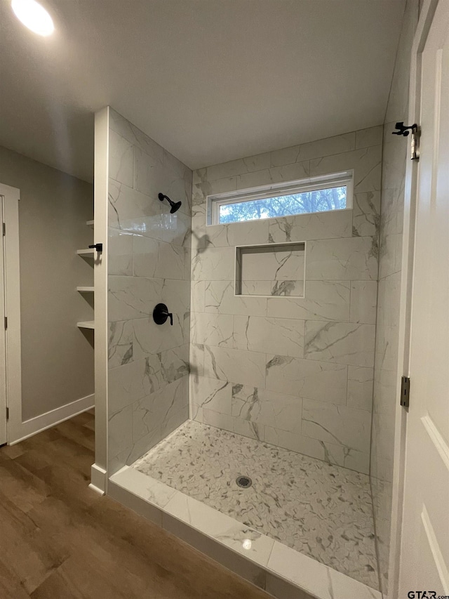 bathroom featuring wood-type flooring and a tile shower