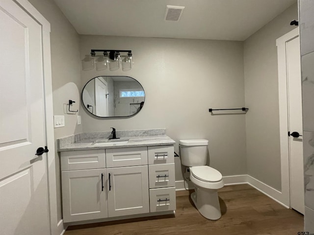 bathroom with wood-type flooring, vanity, and toilet