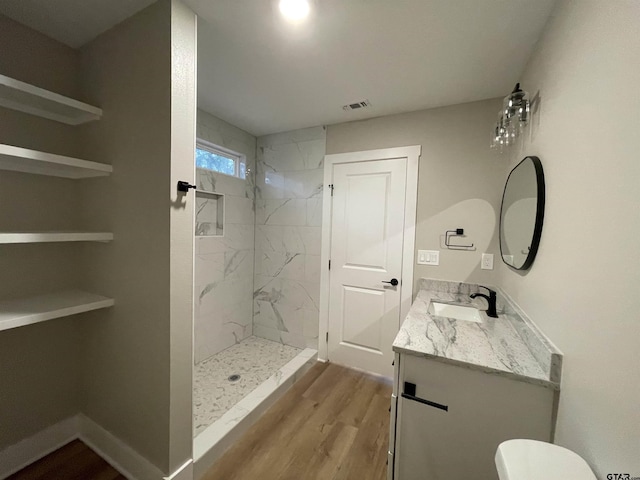 bathroom with vanity, wood-type flooring, and tiled shower