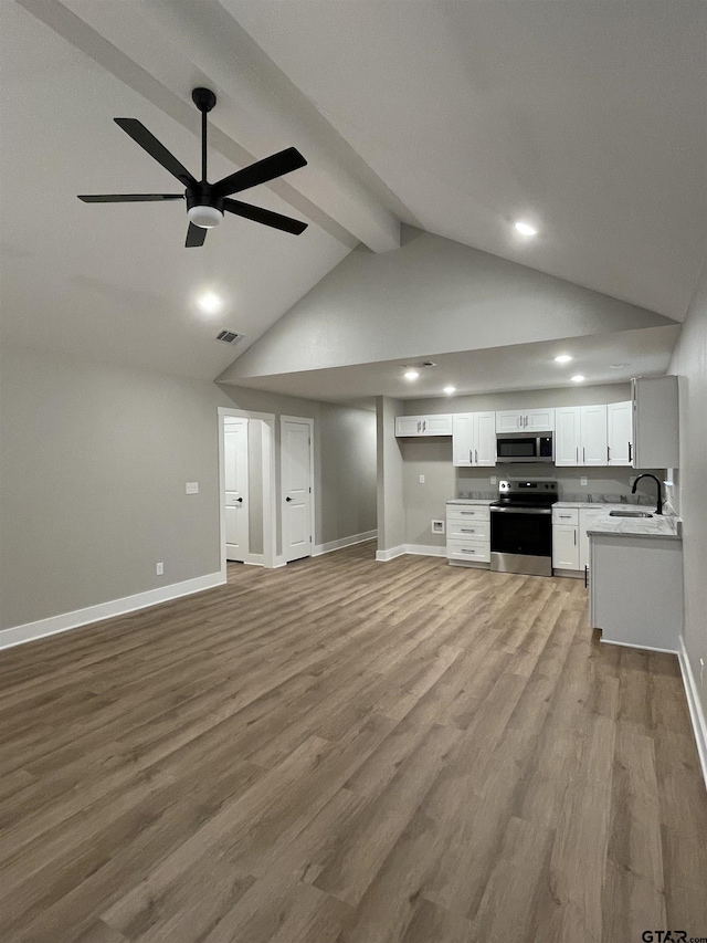 kitchen featuring beam ceiling, white cabinetry, sink, light hardwood / wood-style flooring, and appliances with stainless steel finishes