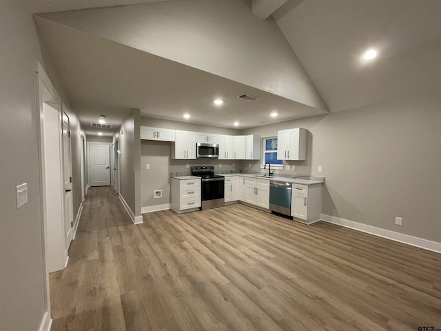 kitchen featuring high vaulted ceiling, white cabinets, sink, light wood-type flooring, and appliances with stainless steel finishes