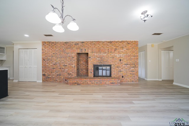 unfurnished living room featuring crown molding, brick wall, a brick fireplace, and light wood-type flooring