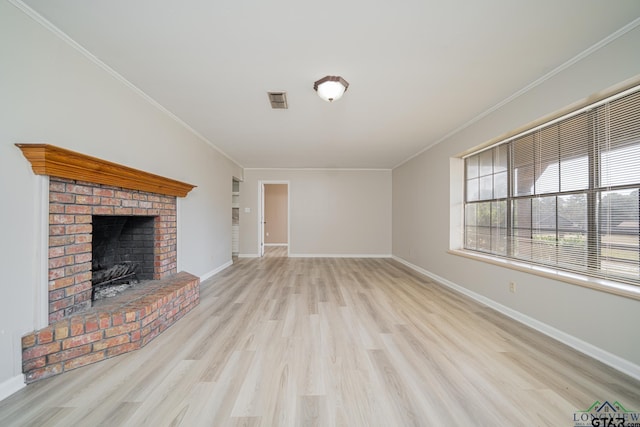 unfurnished living room with crown molding, a brick fireplace, and light hardwood / wood-style floors