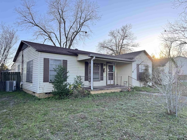 view of front of house featuring a lawn, covered porch, and central air condition unit