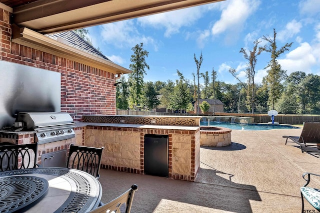 view of patio featuring fence, an outdoor kitchen, grilling area, a fenced in pool, and a fire pit
