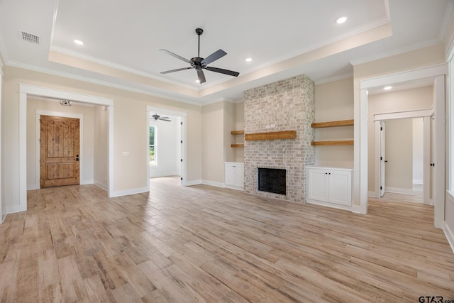 14738 Woodland Creek Dr, Tyler, TX 75706 - unfurnished living room featuring a ceiling fan, a brick fireplace, light wood-type flooring, a raised ceiling, and crown molding