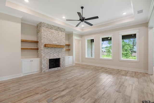 14738 Woodland Creek Dr, Tyler, TX 75706 - unfurnished living room with light wood finished floors, ceiling fan, a brick fireplace, ornamental molding, and a raised ceiling