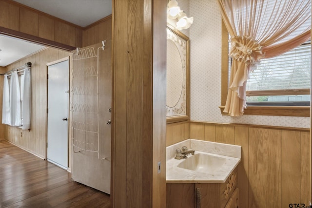 bathroom featuring a wainscoted wall, ornamental molding, wood finished floors, wallpapered walls, and vanity