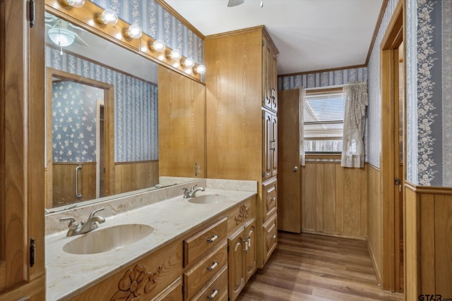 full bath with wood finished floors, wainscoting, wallpapered walls, and a sink