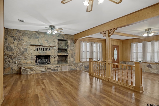 living area featuring visible vents, plenty of natural light, a fireplace, and wood finished floors