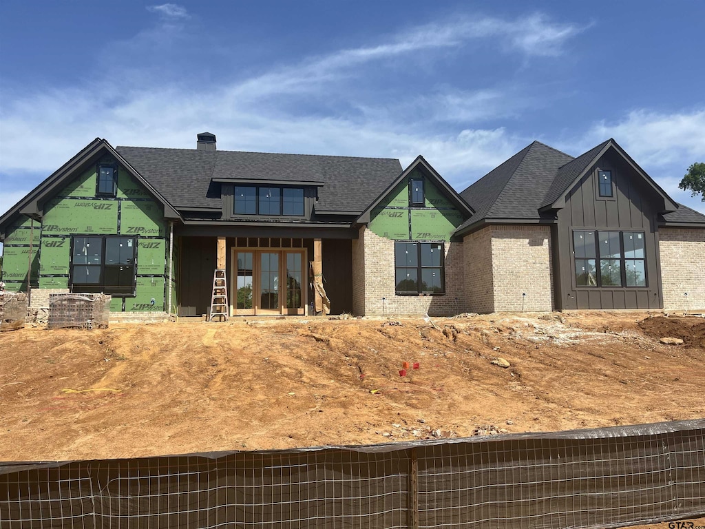 view of front of house featuring brick siding, board and batten siding, and a shingled roof