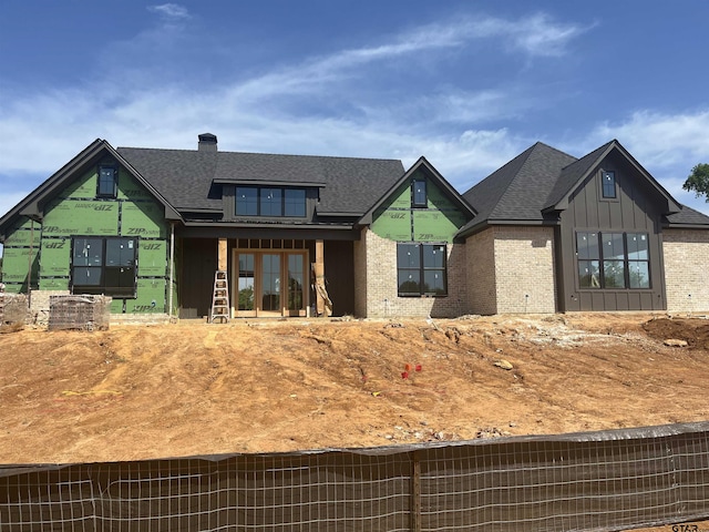 view of front of house featuring brick siding, board and batten siding, and a shingled roof