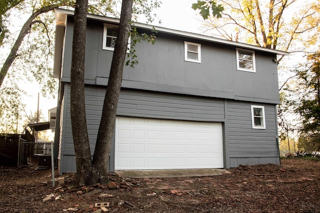 rear view of property featuring a garage and cooling unit