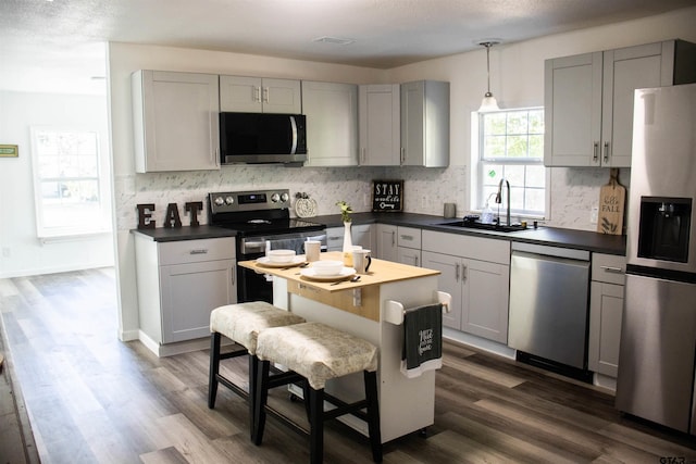 kitchen with stainless steel appliances, gray cabinets, sink, and dark wood-type flooring