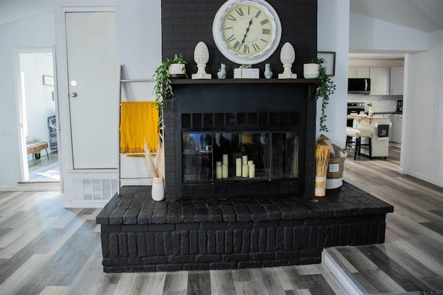 living room featuring lofted ceiling, hardwood / wood-style floors, and a fireplace