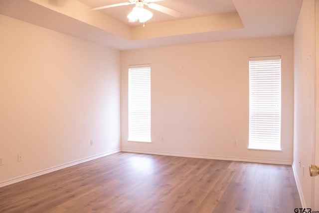 unfurnished room with hardwood / wood-style floors, a tray ceiling, and ceiling fan