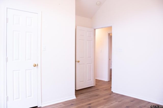 unfurnished bedroom featuring lofted ceiling and light hardwood / wood-style floors