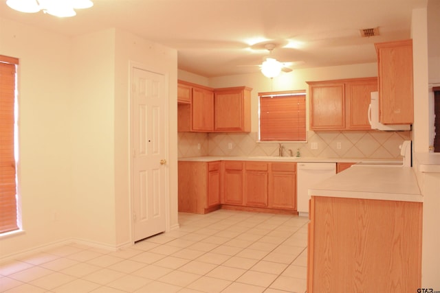 kitchen with light tile patterned flooring, light brown cabinetry, dishwasher, decorative backsplash, and stove