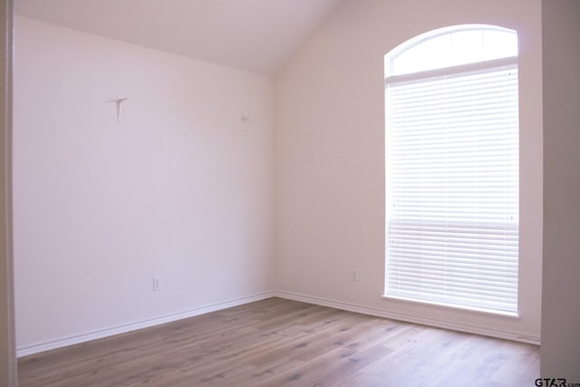 empty room with vaulted ceiling and light wood-type flooring