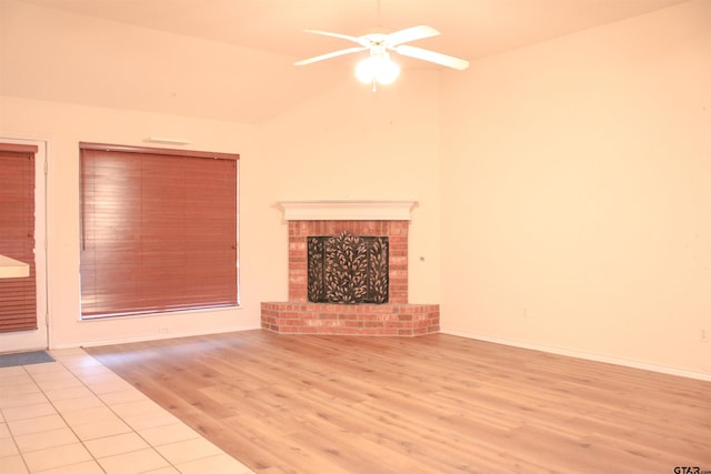 unfurnished living room featuring a brick fireplace, vaulted ceiling, light hardwood / wood-style floors, and ceiling fan